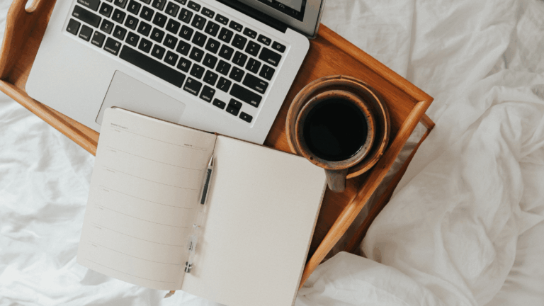 Cozy workspace setup for planning an email marketing campaign, featuring a coffee mug, open laptop, and handwritten to-do list for content strategy.