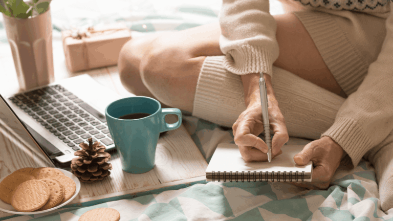 Entrepreneur journaling with coffee on a cozy bed — reflecting and planning during a Sunday reset routine.